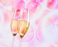 Champagne flutes with golden bubbles on blur petals of roses background Royalty Free Stock Photo