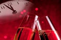 Champagne flutes with golden bubbles on christmas red light bokeh background with vintage alarm clock Royalty Free Stock Photo