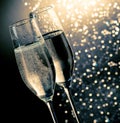 Champagne flutes with golden bubbles on dark blue light bokeh background Royalty Free Stock Photo