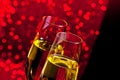 Champagne flutes with golden bubbles on dark red light bokeh background Royalty Free Stock Photo