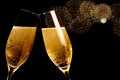 Champagne flutes with golden bubbles make cheers with fireworks sparkle and black background