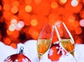 Champagne flutes with golden bubbles on red christmas lights bokeh and balls decoration background Royalty Free Stock Photo
