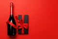Champagne and gift: Celebratory duo on a red background with text space Royalty Free Stock Photo
