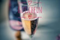 Champagne glass with noble champagne and inscription in pink on german Gutschein, in english coupon, voucher, gift card