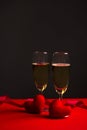 Champagne in glasses of two in romantic valentine concept with heart shaped fabric on red and black background Royalty Free Stock Photo