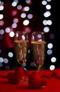 Champagne in glasses of two in romantic valentine concept with heart shaped fabric on red and light bokeh background Royalty Free Stock Photo