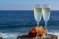 Champagne, prosecco or cava served with pink grape in two glasses on outside terrace with sea view