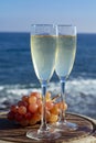 Champagne, prosecco or cava served with pink grape in two glasses on outside terrace with sea view