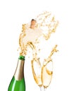 Champagne splashing out of bottle and glasses on background