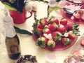 Champagne and  two glass with sweet strawberries and slices on a white background, flowers in a red cup and  branch in the shape o Royalty Free Stock Photo