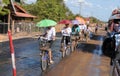 Champasak: Lao people biking with an umbrella in one hand