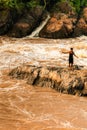 Laotian fisherman stands on the rapid on the Mekong River