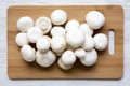 Champignon mushrooms on bamboo board over white wooden background, top view. Royalty Free Stock Photo