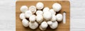 Champignon mushrooms on bamboo board over white wooden background, top view. From above, overhead Royalty Free Stock Photo