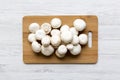 Champignon mushrooms on bamboo board over white wooden surface, top view. Royalty Free Stock Photo