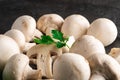 Champignon mushrooms healthy food on black plate with parsley greenery on dark black textured background