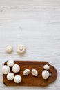 Champignon mushrooms on rustic wooden board over white wooden background, top view. From above. Royalty Free Stock Photo