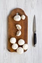 Champignon mushrooms on rustic wooden board over white wooden table, top view. From above, overhead Royalty Free Stock Photo