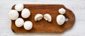 Champignon mushrooms on rustic wooden board over white wooden background, top view. From above Royalty Free Stock Photo