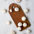 Champignon mushrooms on wooden board over white wooden background, overhead view. From above Royalty Free Stock Photo