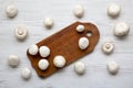 Champignon mushrooms on wooden board over white wooden surface, top view. Royalty Free Stock Photo