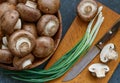 Champignon mushrooms in a wooden bowl and green onions, close-up, top view Royalty Free Stock Photo