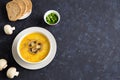 Champignon soup in a white bowl. Whole champignons, bread and cut green onions on a blue background.