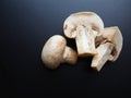 Champignons on a black background. Sliced and whole fresh uncooked raw mushrooms. Cooking mushrooms with a recipe Royalty Free Stock Photo