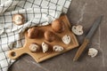 Champignons, knife, board and towel on grey background