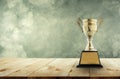 champion golden trophy placed on a wooden table with vintage wall background copy space ready for your design. Royalty Free Stock Photo