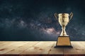 champion golden trophy on wood table with Milky Way background c