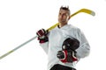 Young male hockey player with the stick on ice court and white background Royalty Free Stock Photo