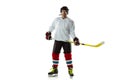 Young male hockey player with the stick on ice court and white background Royalty Free Stock Photo