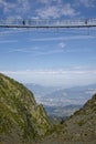 Hikers walk on the new pedestrian Himalayan bridge with the valley and city of Grenoble