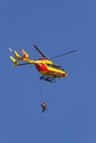 Two people under a rescue helicopter on a blue sky background
