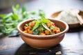 chana masala in a rustic bowl with a mint sprig