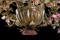 Chandelier close-up classic bronze with curly lampshades flowers and gold leaves.