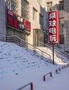 Snow covered staircase with a sunlit part of a gray building, Changchun, China