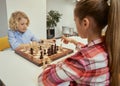 Change with each move. Concentrated little caucasian boy planning his move while playing chess with friend, sitting Royalty Free Stock Photo