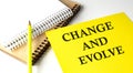 CHANGE AND EVOLVE text written on a yellow paper with notebook Royalty Free Stock Photo