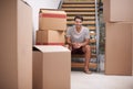 Change is a good thing. A happy young man sitting on the stairs in his home amongst packed cardboard boxes.