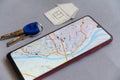 Change of residence concept. Smartphone, door keys and a small paper house. A map of the city of St. Louis on the screen of the