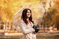 Change of season concept. Dreamy millennial woman using umbrella during her walk at park on rainy autumn day Royalty Free Stock Photo