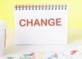 CHANGE the word is written on a blank sheet in a notebook standing on a table on a yellow background