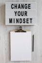 `Change your mindset` words on a modern board, clipboard with blank sheet of paper on a white wooden background, overhead view. Royalty Free Stock Photo