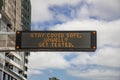 Changeable electronic dynamic road sign reads: -Stay COVID safe. Unwell. Get tested- on the city road. Coronavirus
