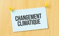 Changement climatique sign written on sticky note pinned on wooden wall