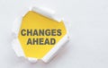 CHANGES AHEAD text appears under torn white paper on yellow background Royalty Free Stock Photo