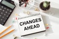 CHANGES AHEAD text written on white notepad with calculator,pencil and green plant on office desk Royalty Free Stock Photo