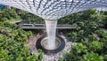 Changi Airport, Singapore - February 18, 2023 - Top view of the indoor waterfall at Jewel and the Skytrain passing the Rain Vortex